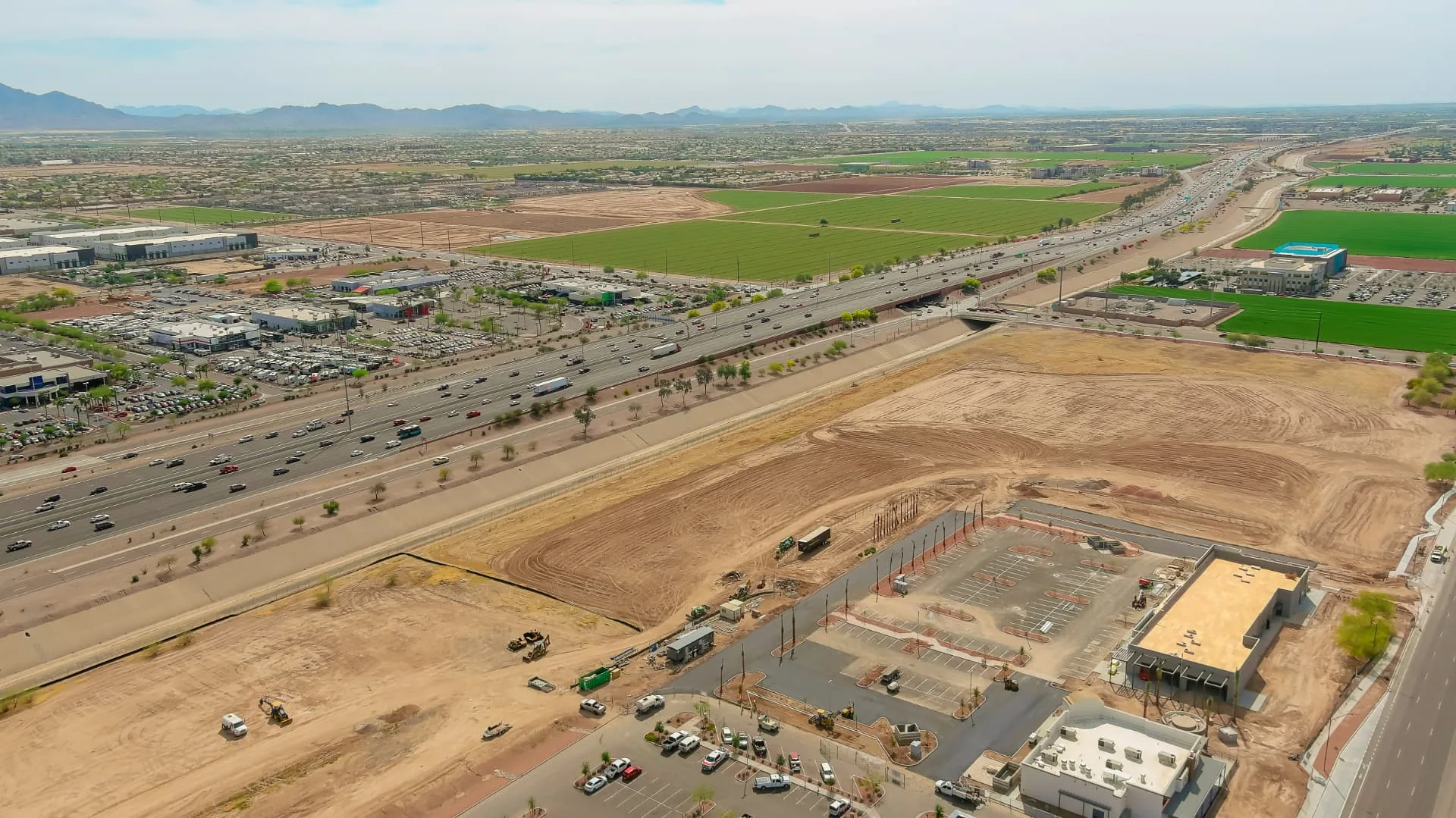 Aerial view of a Phoenix area highway corridor with newly graded commercial pads and parking lots