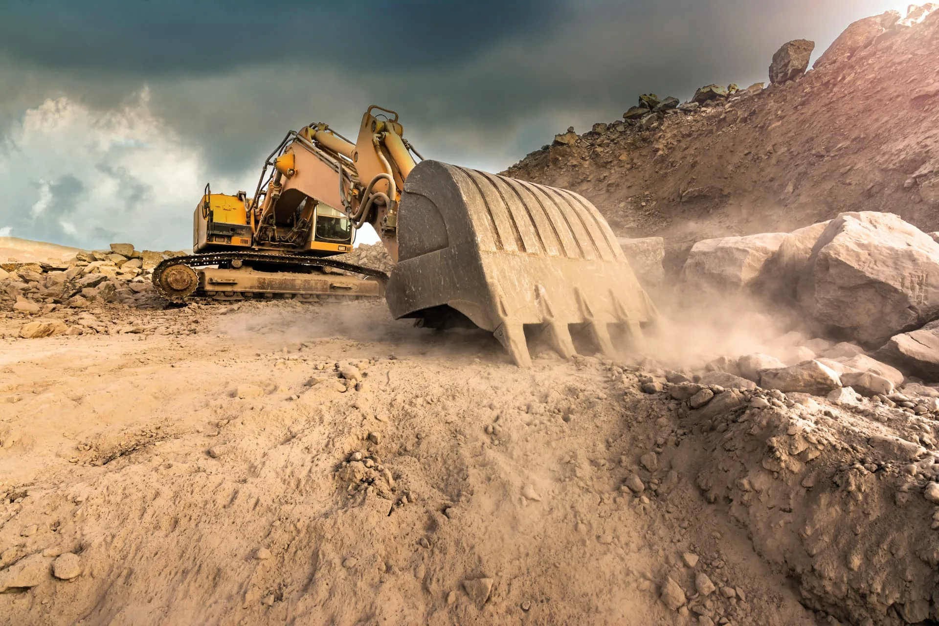 Excavator cutting into a rocky hillside during grading work near Phoenix, AZ