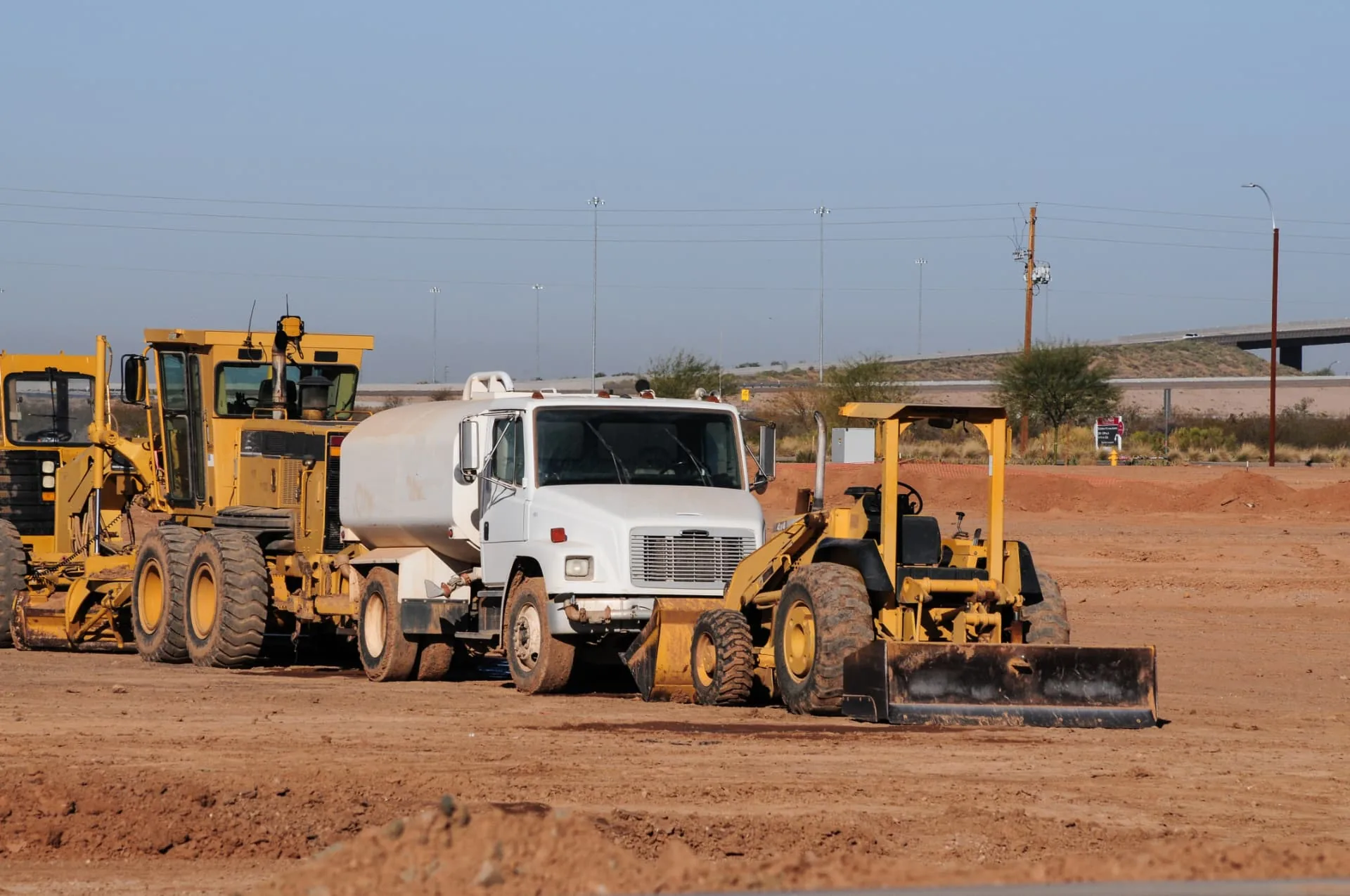 Motor grader, water truck and wheel loader on a freshly graded building pad in Phoenix, AZ